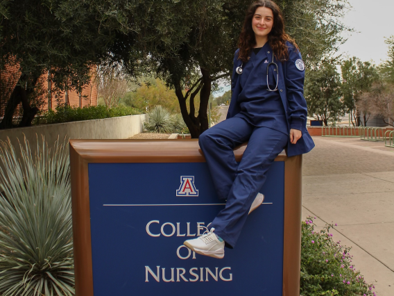 Photos Melissa Hailey sitting on a College of Nursing sign